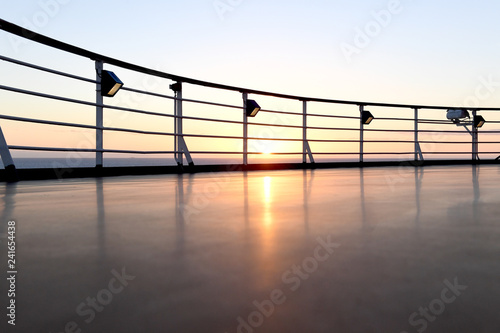 Railing and deck flooring of a cruise ship at sunset with the ocean in the background. © scottdavis2