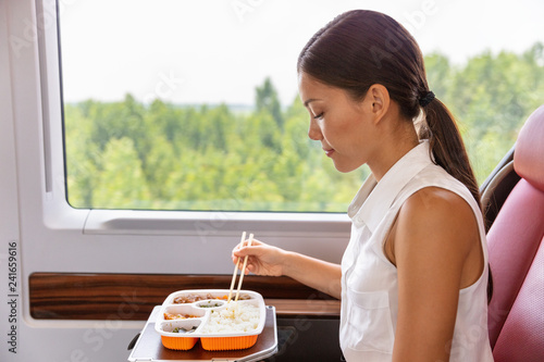 Train commute bus travel Asian business woman eating asian food meal with chopsticks. Businesspeople commuting eating lunch.