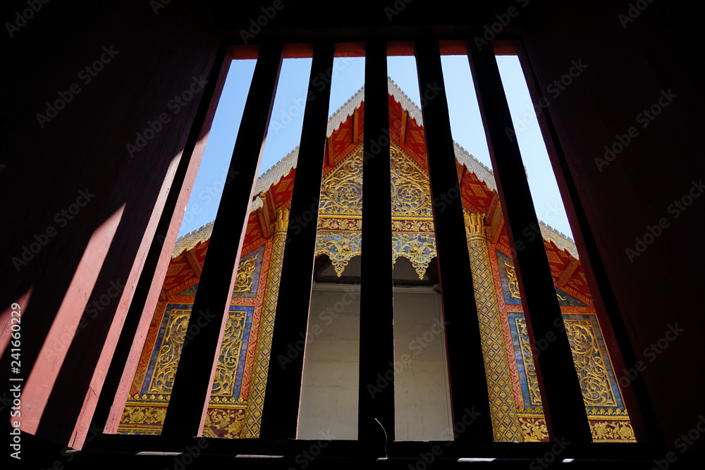 Chiangmai , Wat phra signh Temple in frame of window with light of shadow. Wat Phra Singh is a Buddhist temple in ChiangMai , Northern of Thailand.. Chiangmai , Wat phra signh Temple in frame of window with light of shadow. Wat Phra Singh is a Buddhist temple in ChiangMai , Northern of Thailand..