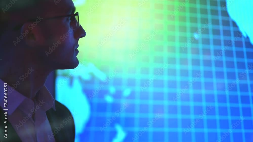 The businessman in glasses standing near a big screen on hologram background The businessman in glasses standing near a big screen on hologram background