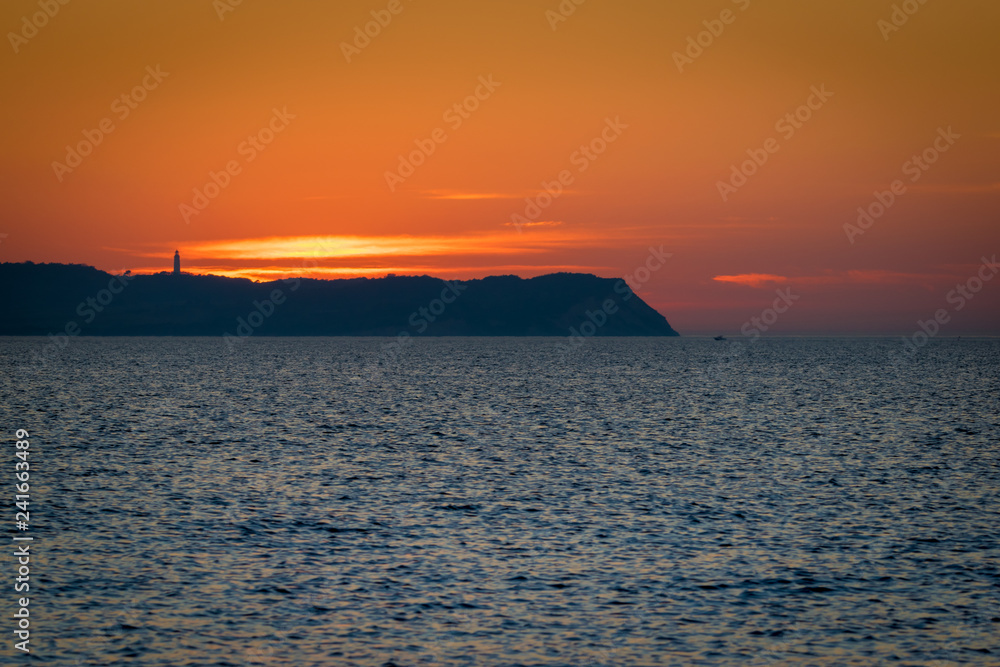 Sonnenuntergang hinter Insel Hiddensee mit Leuchtturm Dornbusch