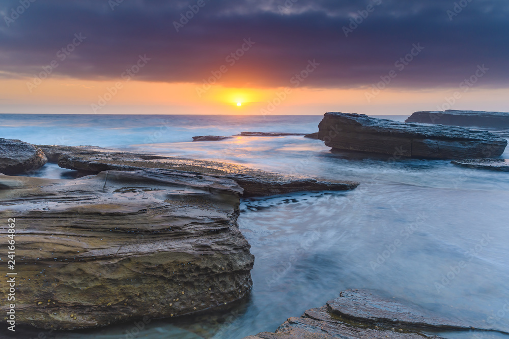 An Atmospheric Sunrise Seascape with Large Rocks