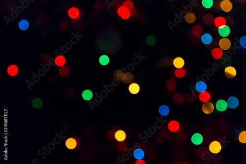 Abstract festive New Year Christmas defocused background with bokeh multicolored effect on black background with copy space.