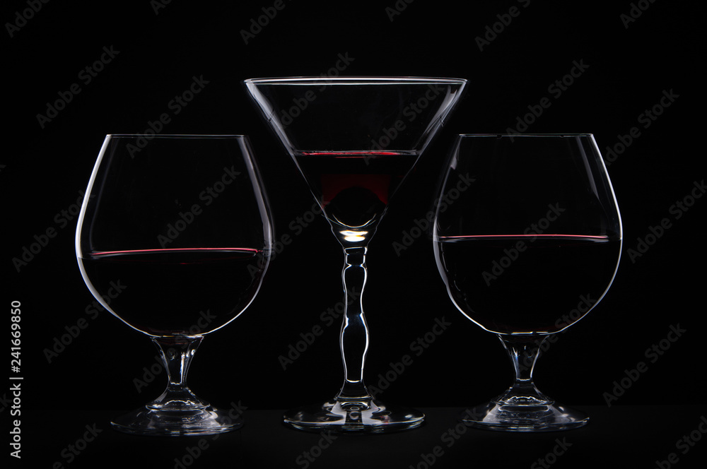Silhouette of  three drinking glass and red wine on black background 
