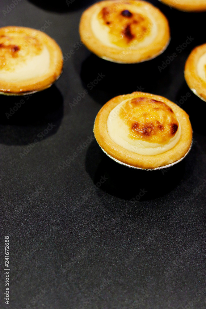 Fresh baked Hokkaido cheese tarts on a black background with copy space Fresh baked Hokkaido cheese tarts on a black background with copy space