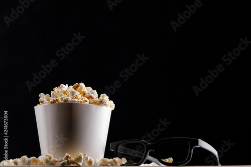 Large paper cup with popcorn and glasses on a close background. Copy space.