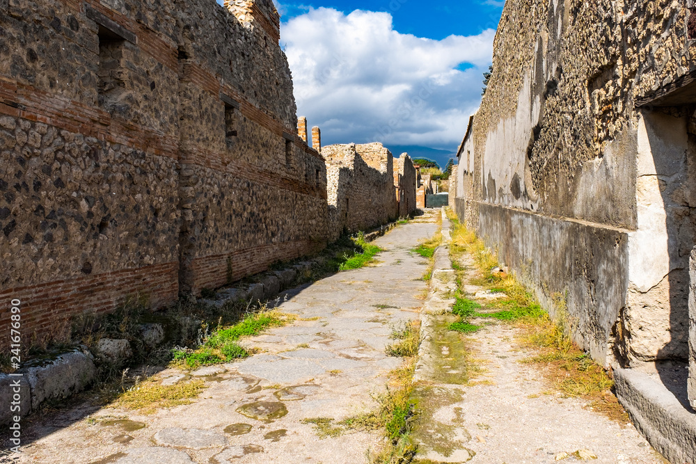 An ancient cobbled street in the ruins of Pompeii. Roman town destroyed by Vesuvius volcano. An ancient cobbled street in the ruins of Pompeii. Roman town destroyed by Vesuvius volcano.