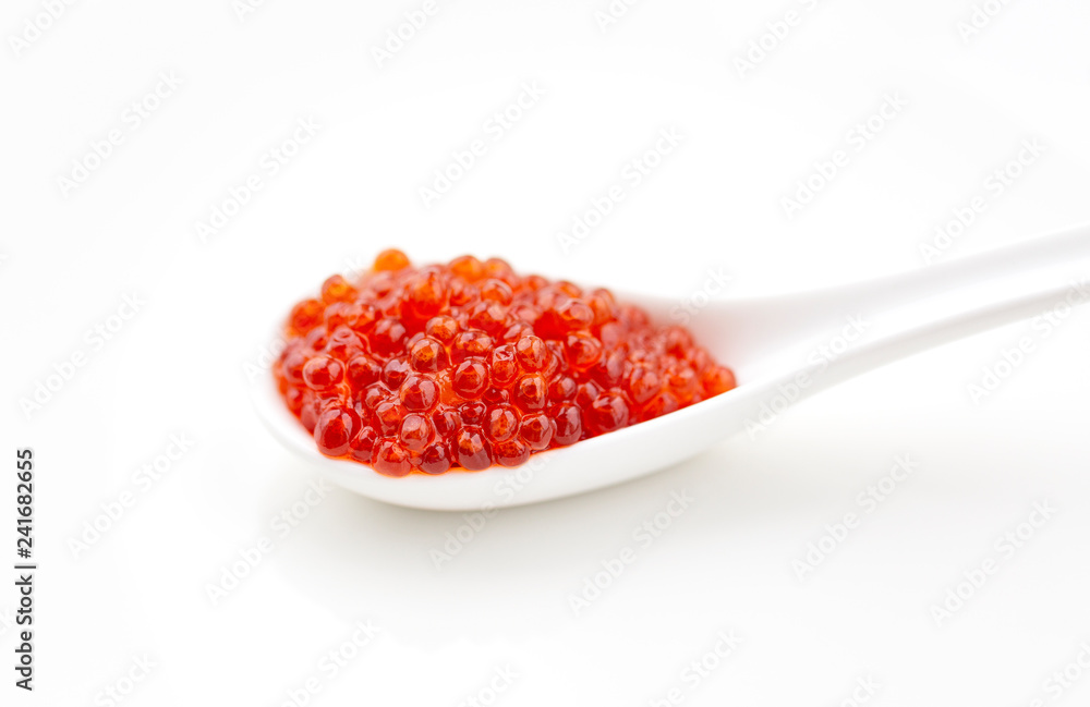 Porcelain spoon with red caviar isolated on white background. Close-up. Porcelain spoon with red caviar isolated on white background. Close-up.