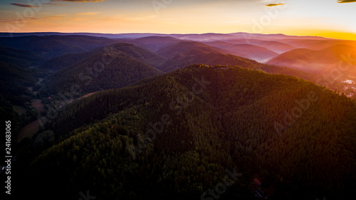 Aerial drone bird's eye view photo of european village of central europe with red roofs and cozy streets, beautiful natural morning sun lights and a fog in the valley