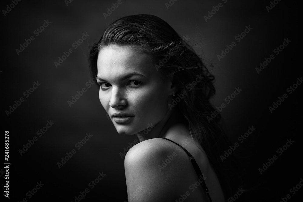 Dramatic black and white portrait of a beautiful girl on a dark background