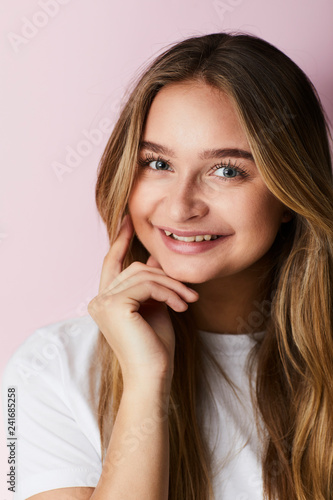 Young girl smiling against pink background