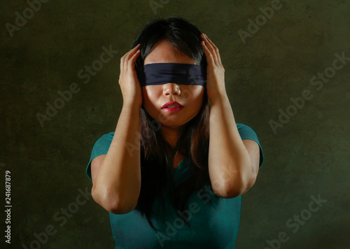 young scared and blindfolded Asian Chinese teenager girl lost and confused playing dangerous internet viral challenge isolated on dark background