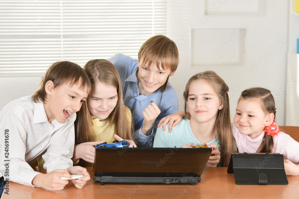 Portrait of funny boys and girls playing computer game together at the table at home Portrait of funny boys and girls playing computer game together at the table at home