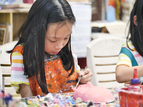 Asian girl painting plaster mask in artist workshop, lifestyle concept.