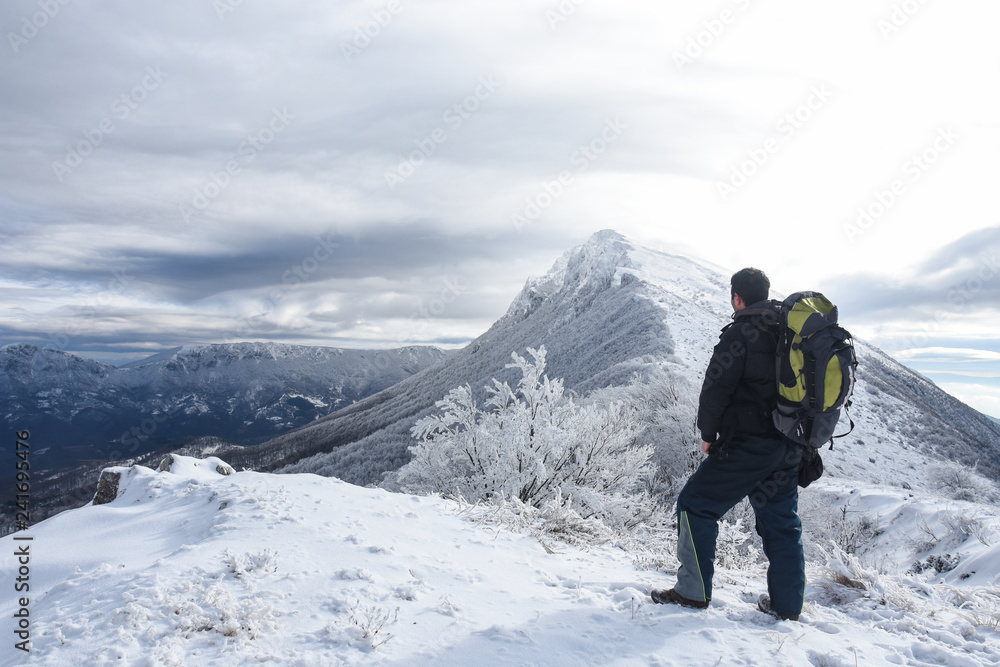 Hiker in a winter mountains. Concept of healthy lifestyle and successful climb,  hiking in nature. Winter background