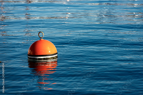 Red and orange mooring buoy in the sea photo