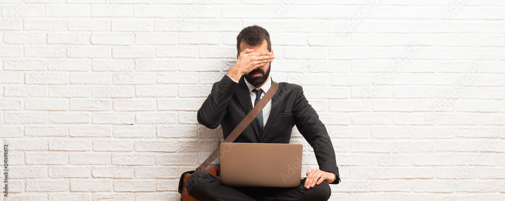 Businessman with his laptop sitting on the floor covering eyes by hands. Do not want to see something Businessman with his laptop sitting on the floor covering eyes by hands. Do not want to see something