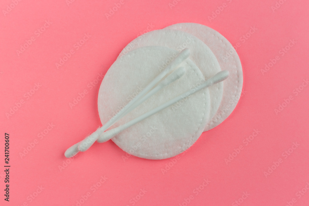 Cotton buds, cotton round pads on pink background. Close-up photo, flat lay, top view.
