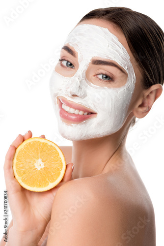 beautiful smiling woman with facial skin care mask holding orange and looking at camera isolated on white