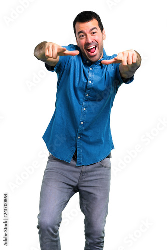 Handsome man with blue shirt pointing with finger at someone and laughing a lot