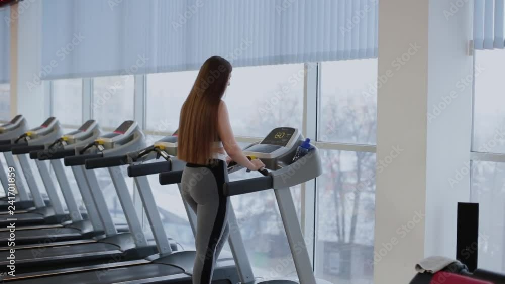 Very beautiful woman getting ready for running on a treadmill in the gym. Very beautiful woman getting ready for running on a treadmill in the gym.