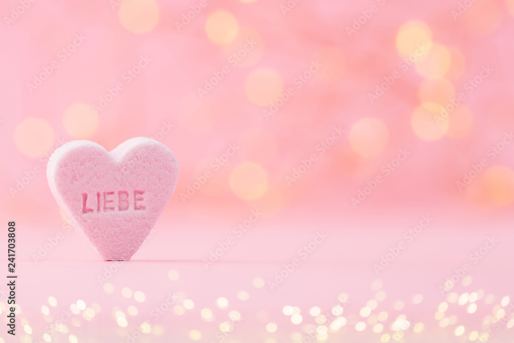 Pastel colored candy hearts in a bokeh background.