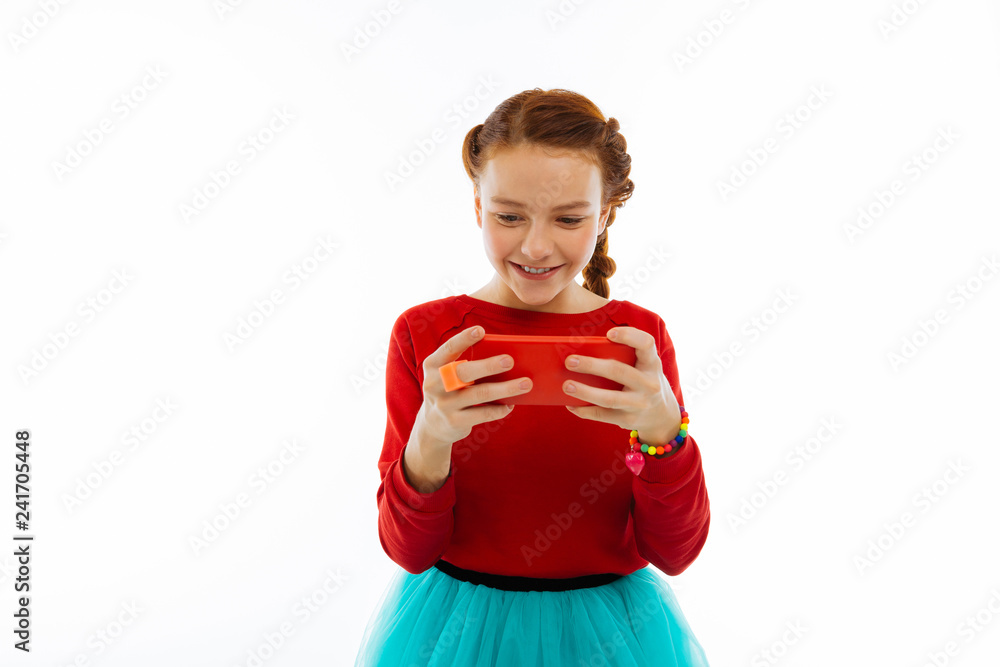 Joyful positive girl playing on her smartphone Joyful positive girl playing on her smartphone