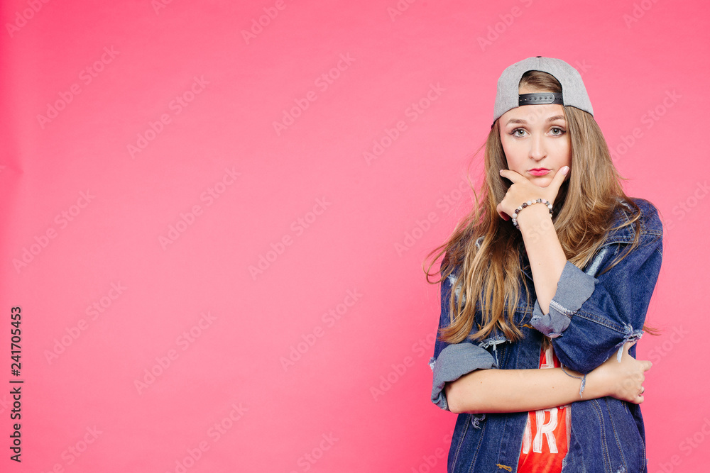 Stockfoto Young serious teen posing with hands near chin, confident looking camera. Swag blondie in cap with long hair thinking. Concept of teen fashion and look. | Adobe Stock