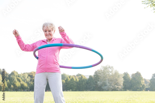 Obraz na płótnie Senior woman doing gymnastic with hula hoop in park