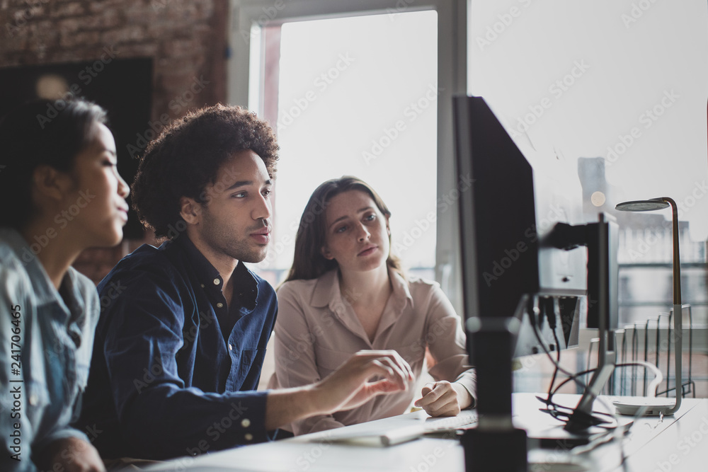 © ReeldealHD images - Coworkers looking at a desktop computer together
