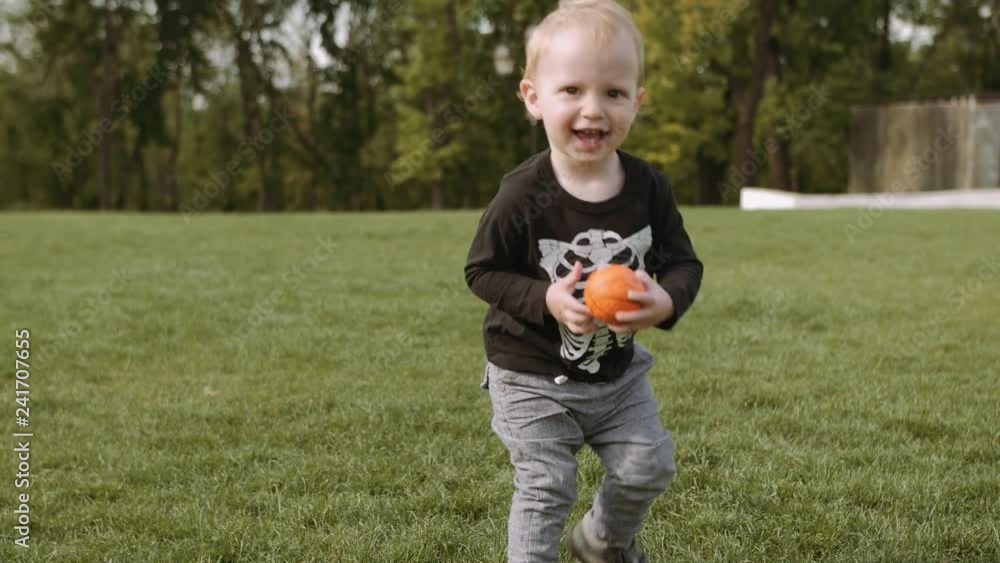 Cute little boy playing with small ball outdoors. Child having fun with family at summer. Kid playing ball on the nature. Happy family time. 