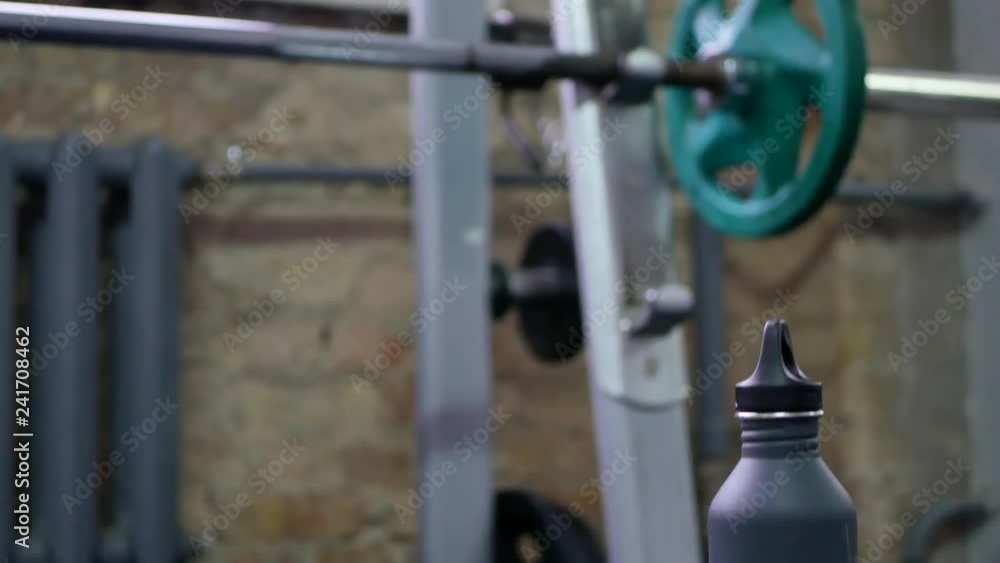 vertical panning shot in a gym starting from water bottle and towel and look up on chest bench with barbell. closeup 4k video footage vertical panning shot in a gym starting from water bottle and towel and look up on chest bench with barbell. closeup 4k video footage