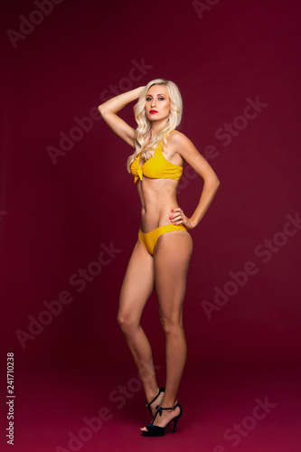 Young and beautiful woman in swimsuit over red background.