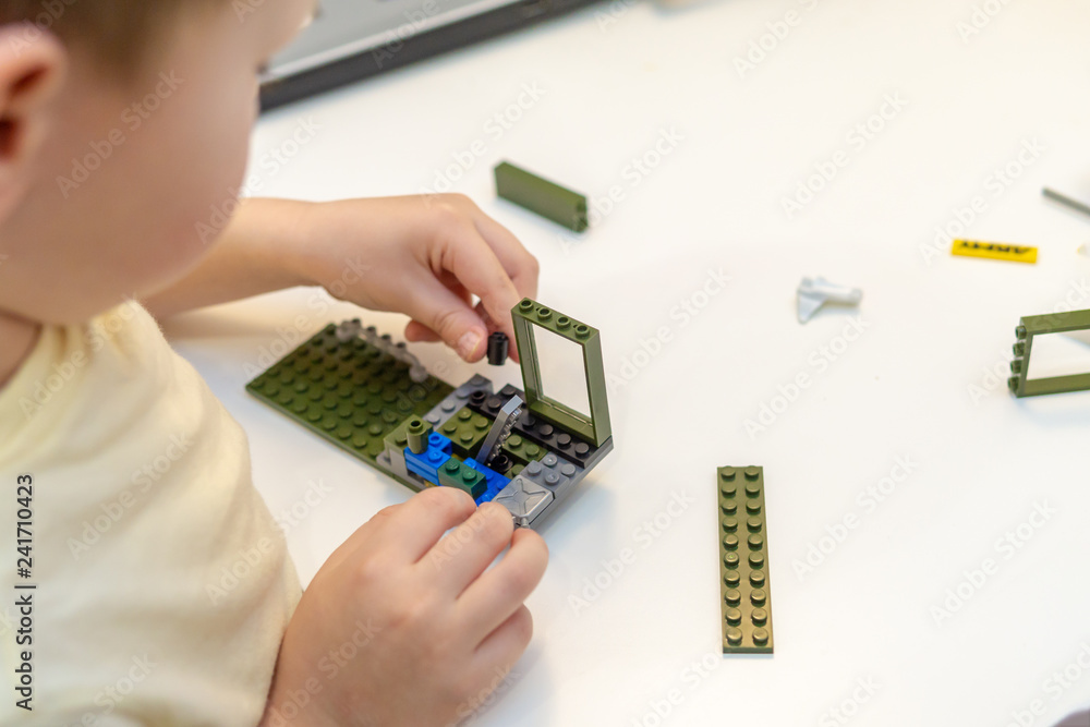Little boy playing with constructor in the room. The concept of loneliness, expectations, an orphan boy, an orphanage. Education image from a kindergarten: child playing with toys at his table Little boy playing with constructor in the room. The concept of loneliness, expectations, an orphan boy, an orphanage. Education image from a kindergarten: child playing with toys at his table