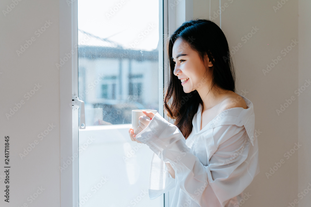 Asian woman drinking coffee in the morning breakfast in window bedroom fresh start the day happiness relax at home healthy lifestyle