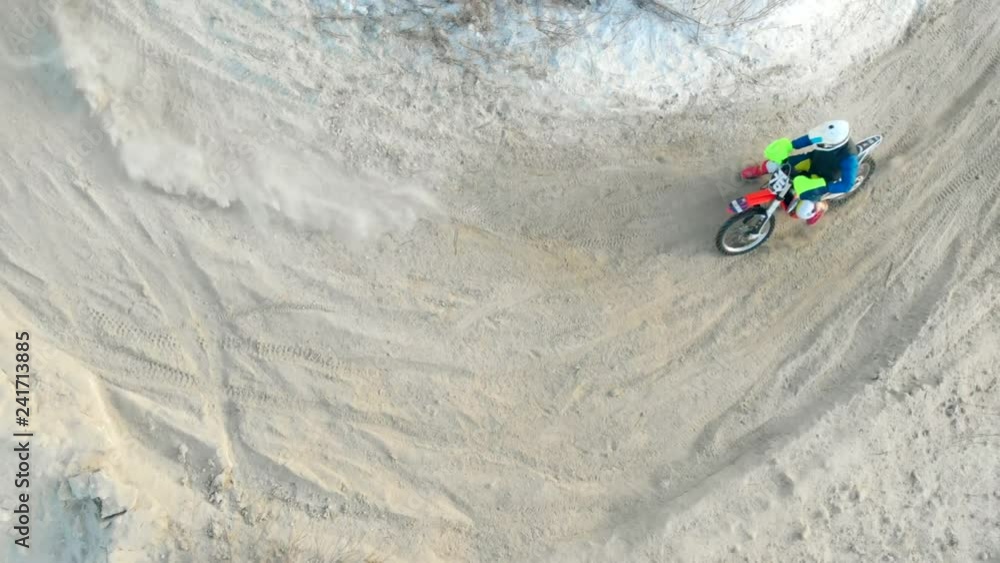 Aerial: Birds eye view of a motocross men riders riding snow track in winter. Winter sports motobike riding. Snow motocross racing aerial video. Aerial: Birds eye view of a motocross men riders riding snow track in winter. Winter sports motobike riding. Snow motocross racing aerial video.