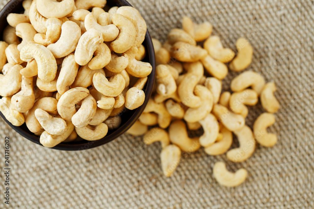 Cashew nuts in a wooden bowl on a burlap cloth background. Cashew nuts in a wooden bowl on a burlap cloth background.