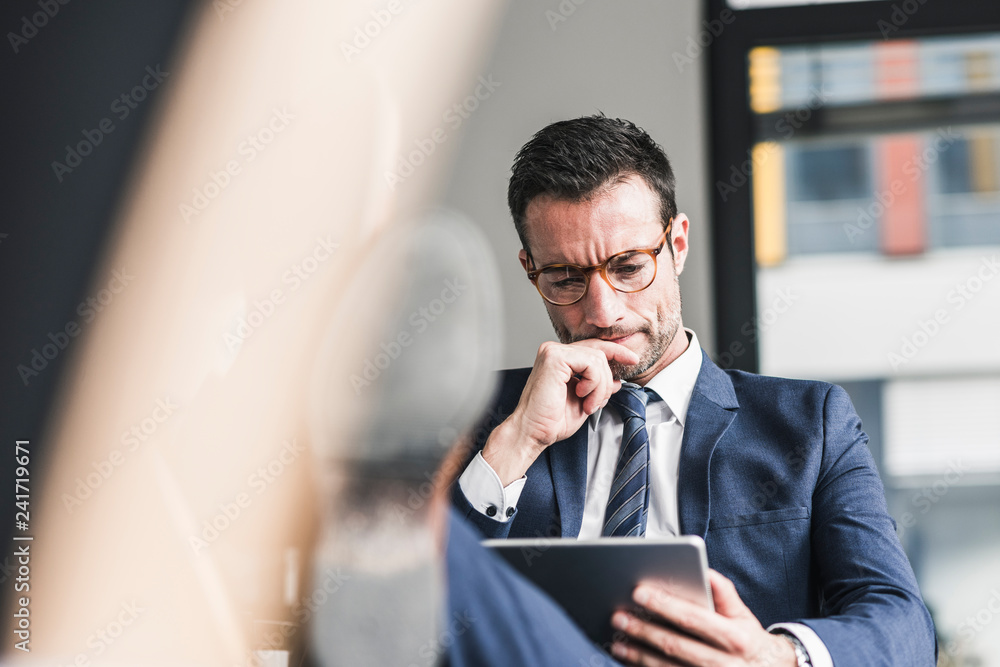 Businessman using digital tablet, sitting in office with feet up Businessman using digital tablet, sitting in office with feet up