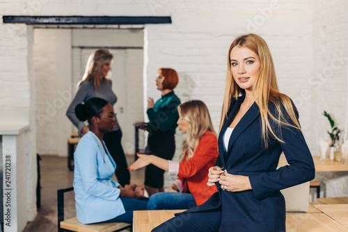 Content satisfied blonde female secretary in trendy formal wear posing in office after meeting with colleagues.