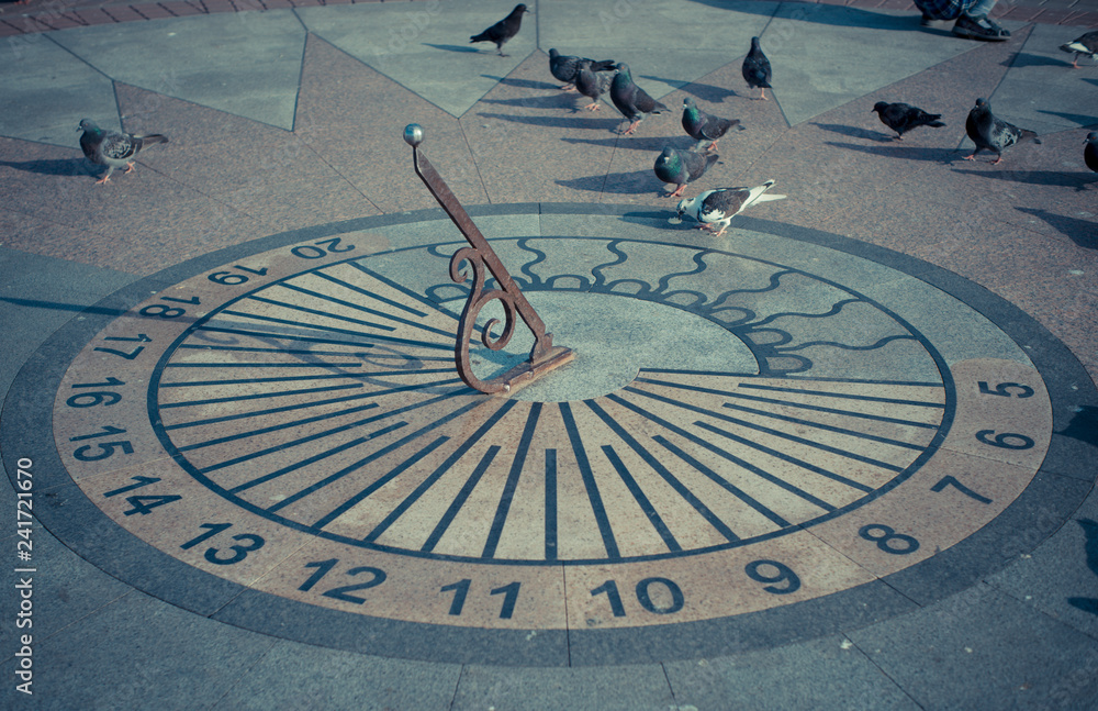 Sundial with pigeons on the waterfront of the city