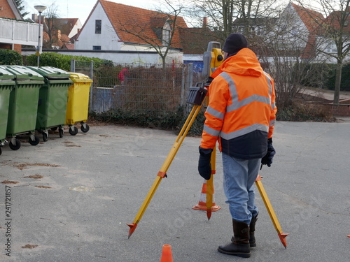 Surveyor, a civil engineer with surveying equipment to prepare a construction site