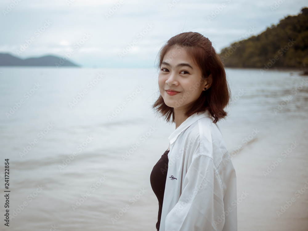 Asian girl looking over shoulder while standing on tropical beach. Portrait of happy young woman smiling at sea. sweet smile. Vintage Tone. copy space.. Asian girl looking over shoulder while standing on tropical beach. Portrait of happy young woman smiling at sea. sweet smile. Vintage Tone. copy space..
