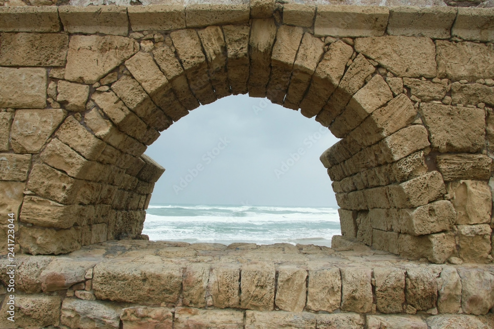 The arches of the ancient Roman aqueduct in Caesarea (Israel) are covered with sand and overgrown with grass