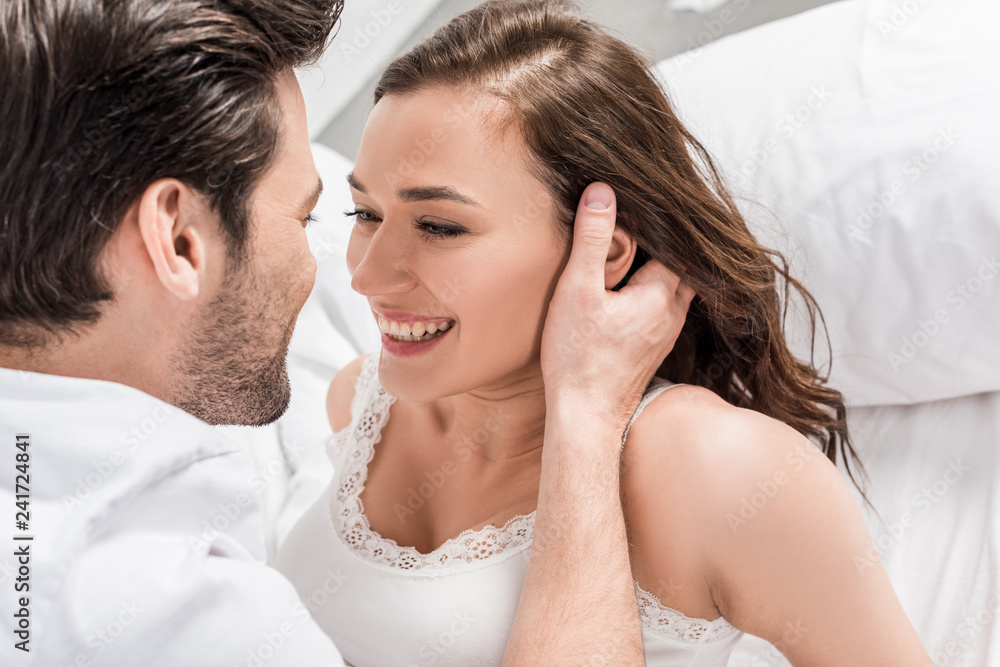 man tenderly touching face of beautiful smiling woman in bed man tenderly touching face of beautiful smiling woman in bed