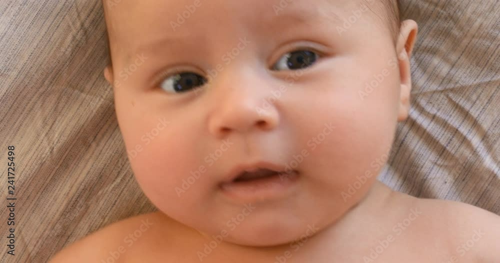 Portrait of cute adorable baby boy lying down and smiling first time on white bed background. Newborn baby smiling and feel happy at home Portrait of cute adorable baby boy lying down and smiling first time on white bed background. Newborn baby smiling and feel happy at home