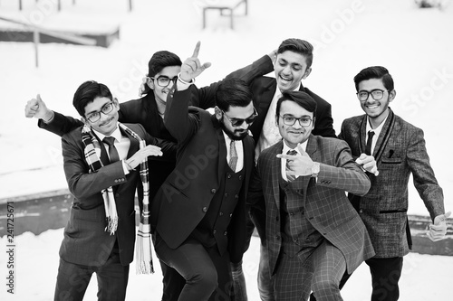Group of six indian businessman in suits posed outdoor in winter day at Europe, hugs and happy emotions.