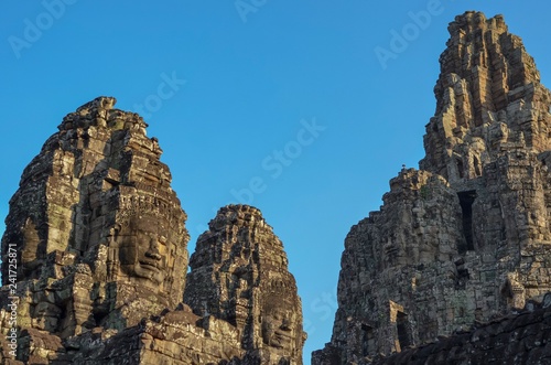 Faces of ancient Bayon Temple at Siem Reap in Cambodia with blue color background from the sky.