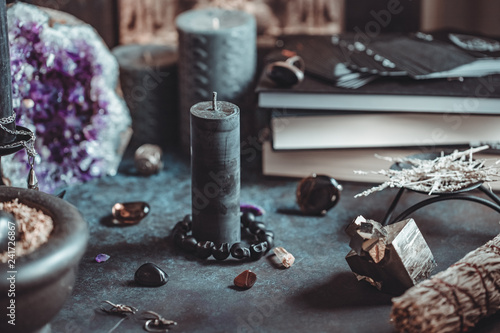Black candle on a witch's altar for a magical ceremony among crystals and black candles. photo