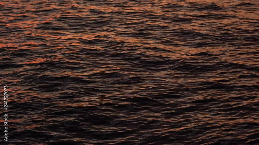 Sea or ocean water wave with sun reflections during sunset. Liquid textured surface background. Close up dramatic real water ripple on the surface of the sea, establishing shot Sea or ocean water wave with sun reflections during sunset. Liquid textured surface background. Close up dramatic real water ripple on the surface of the sea, establishing shot