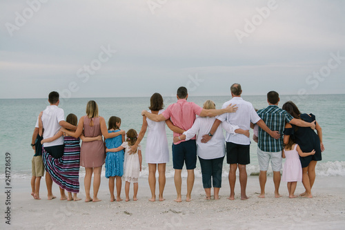 Huge Happy Traveling Caucasian Family with Adults and Kids at the Beach Hugging and Embracing while facing the Ocean Horizon Outside on Destination Vacation © MeganMahoneyPhotos